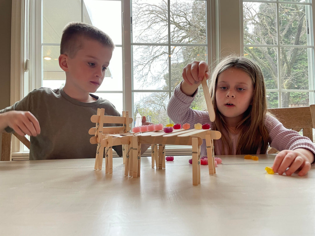 kids balancing gummy bear on popsicle sticks and clothespins STEM activity